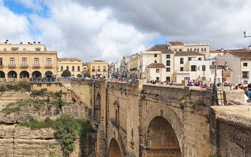 Puente Nuevo bridge in Ronda, Spain, with tourists exploring the historic architecture.