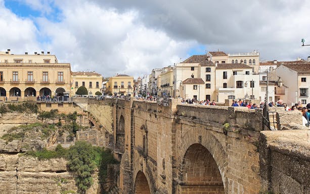 Puente Nuevo bridge in Ronda, Spain, with tourists exploring the historic architecture.