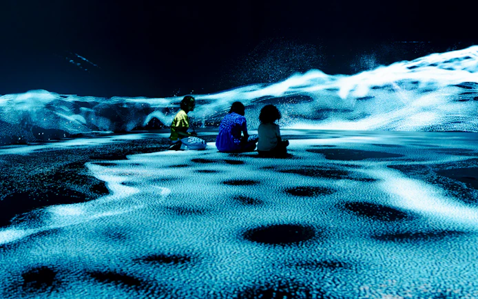 Children sitting in an immersive digital art display at the London Timewalk Exhibition.