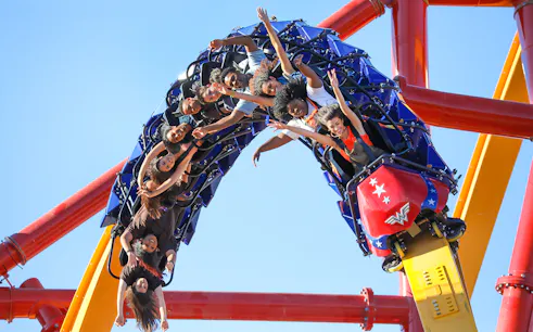 Riders on WONDER WOMAN™ Flight of Courage roller coaster at Six Flags Magic Mountain.