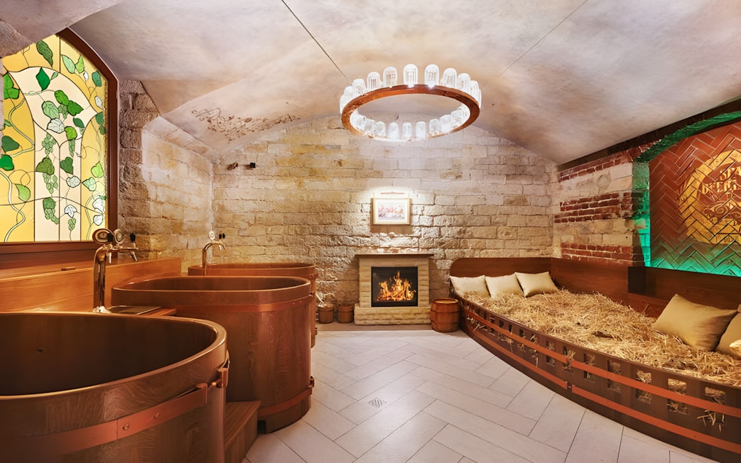 Spa Beerland interior with wooden beer tubs, cozy fireplace, and stained glass window.