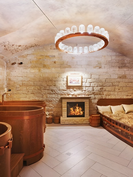 Spa Beerland interior with wooden beer tubs, cozy fireplace, and stained glass window.