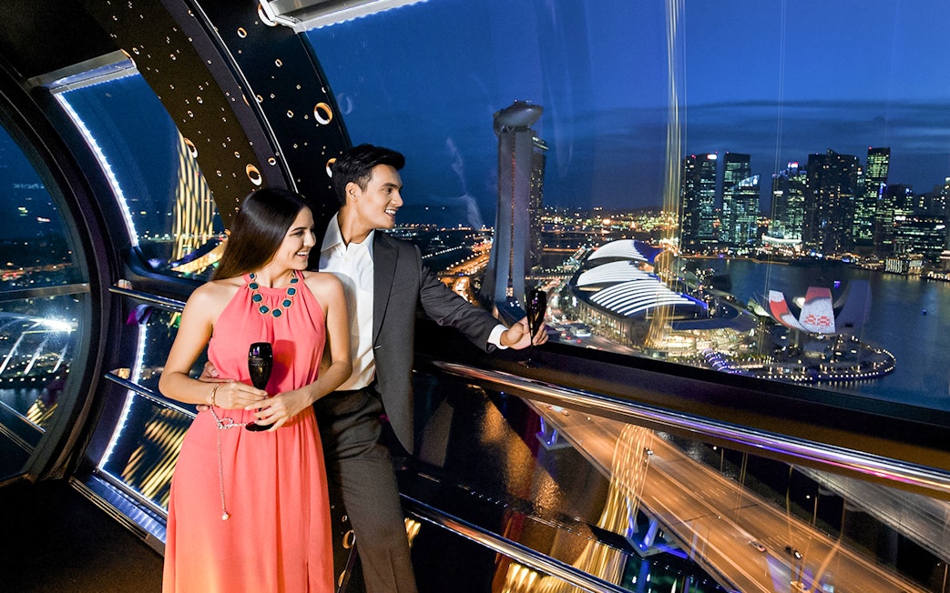 Couple enjoying champagne at 165 Sky Dining, Singapore Flyer with city skyline view.