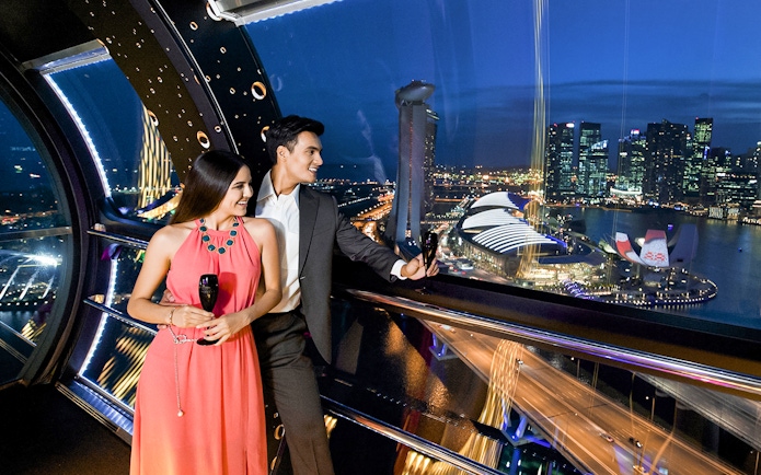 Couple enjoying champagne at 165 Sky Dining, Singapore Flyer with city skyline view.