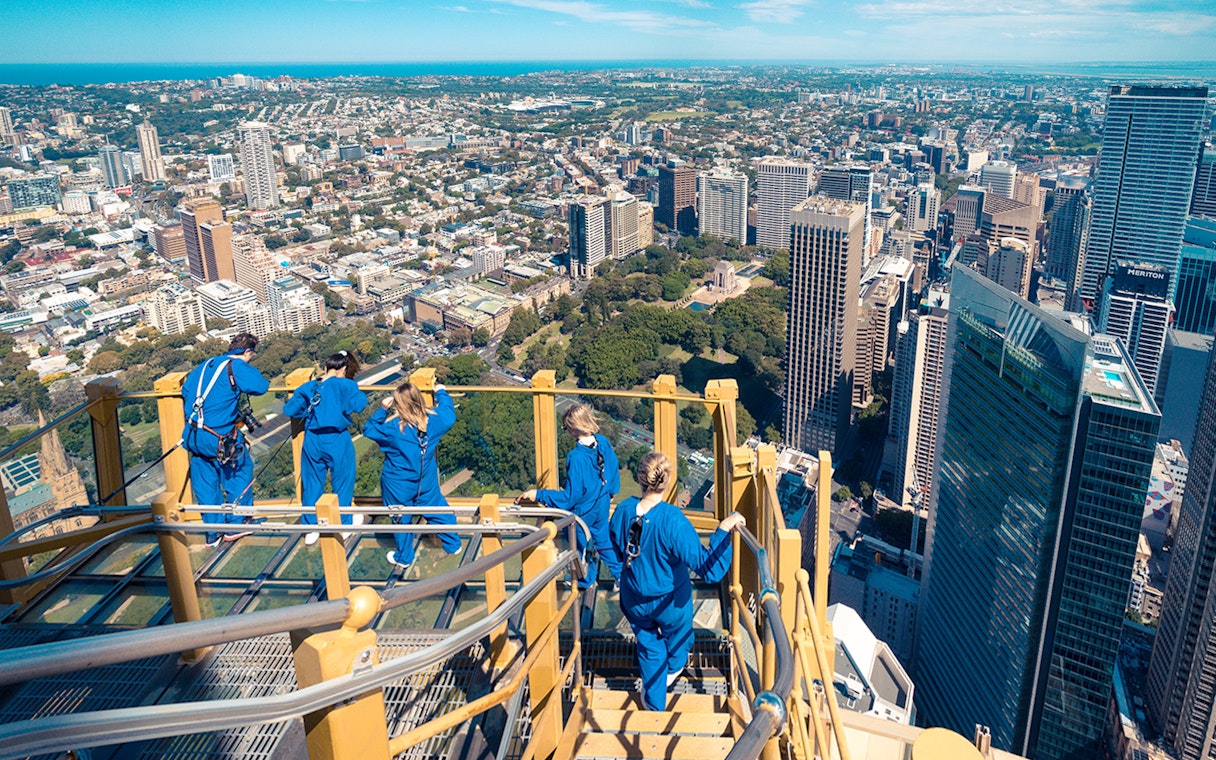 Visitors on Skywalk at Sydney Tower Eye overlooking cityscape.