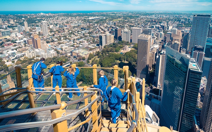 Visitors on Skywalk at Sydney Tower Eye overlooking cityscape.
