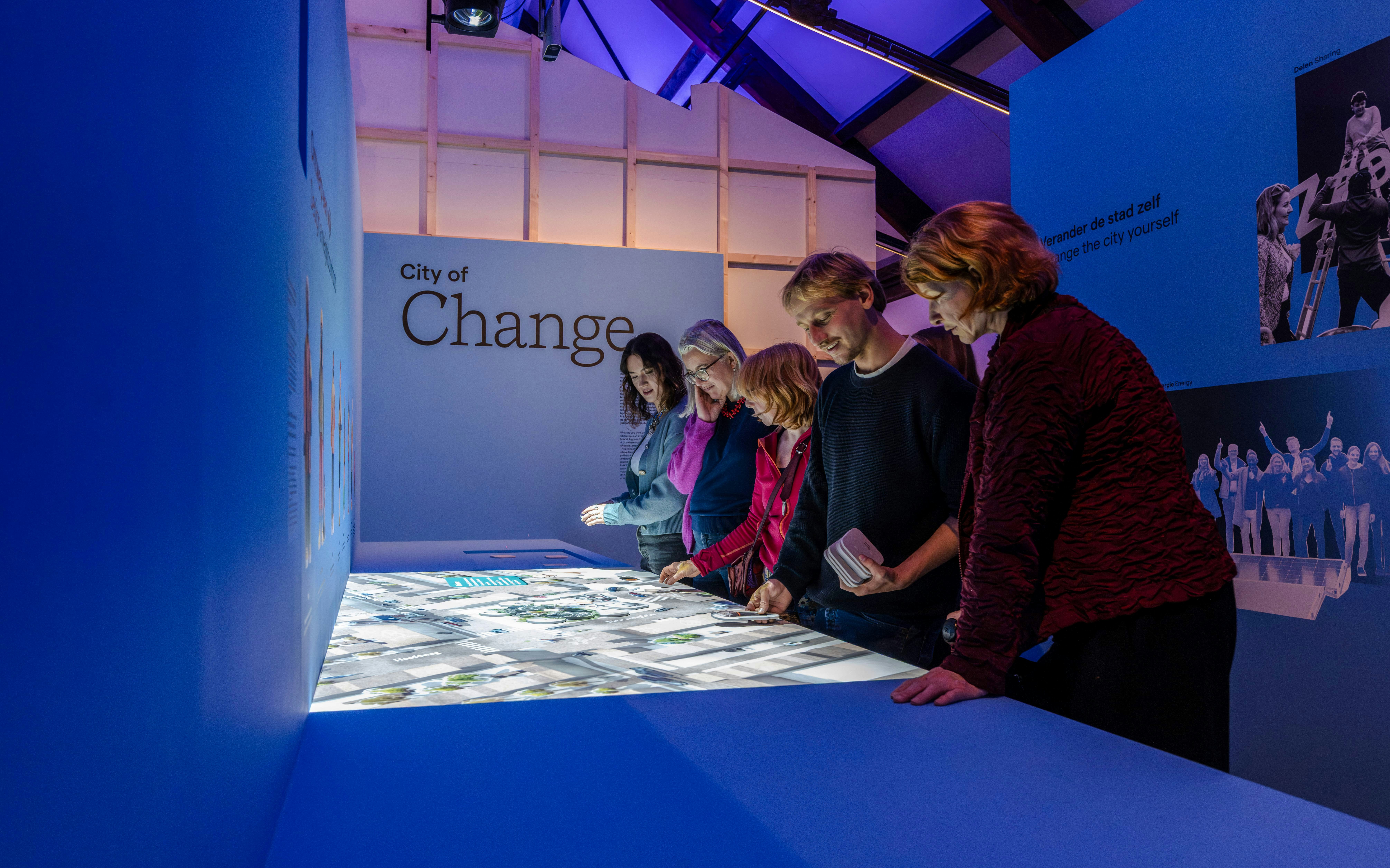 Visitors engaging with interactive exhibit at Amsterdam's "City of Change" display.