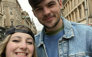Couple smiling on a street in Glasgow during a self-guided city exploration game.