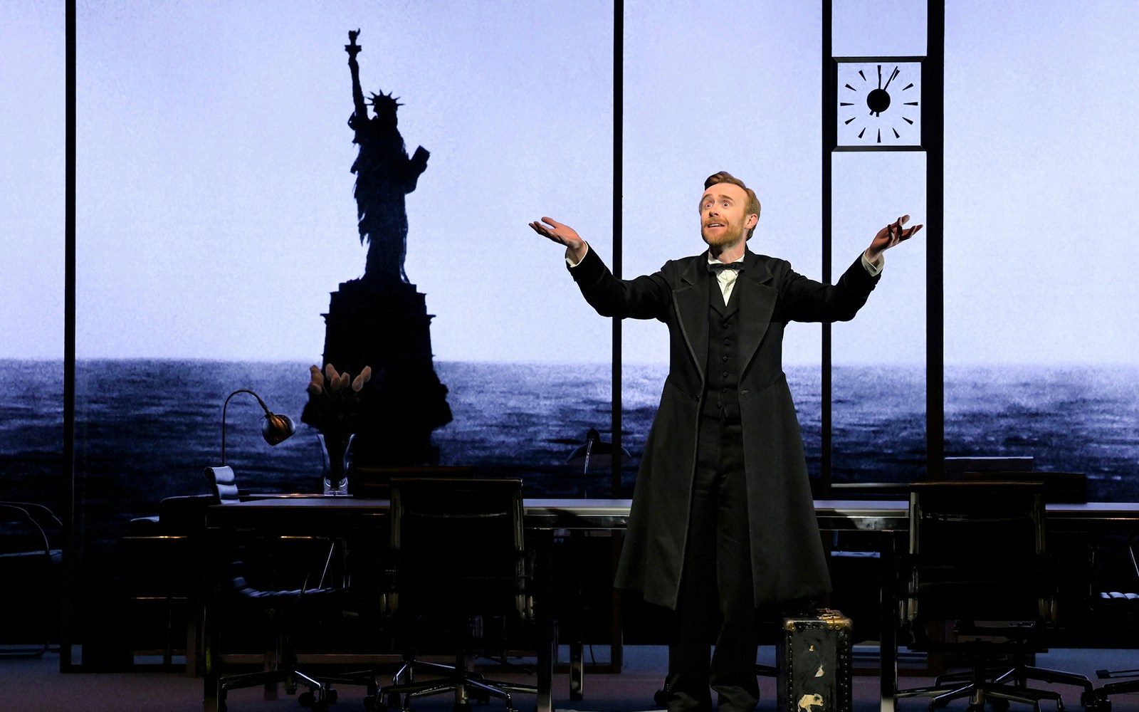 Actor on stage during "The Lehman Trilogy" with Statue of Liberty backdrop.