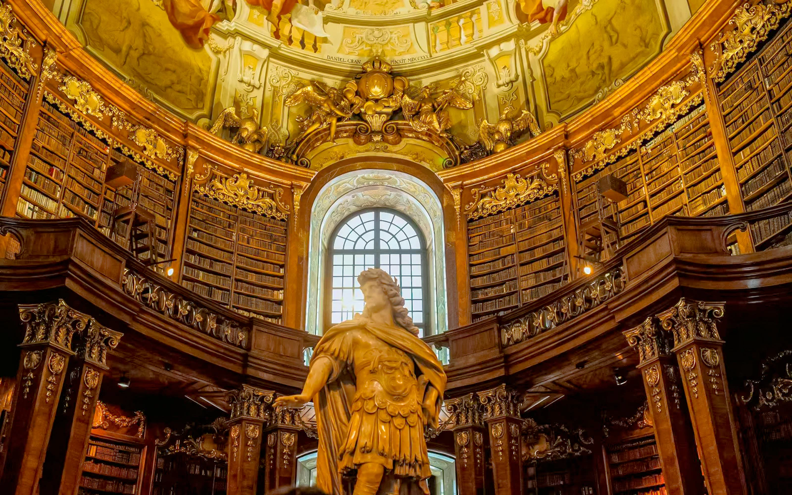 Marble statue of Emperor Charles VI under the ornate dome in the State Hall of the Austrian National Library, Vienna.