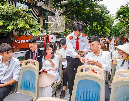 Passengers on Haanoi city hop-on hop-off tour bus reviewing brochures.