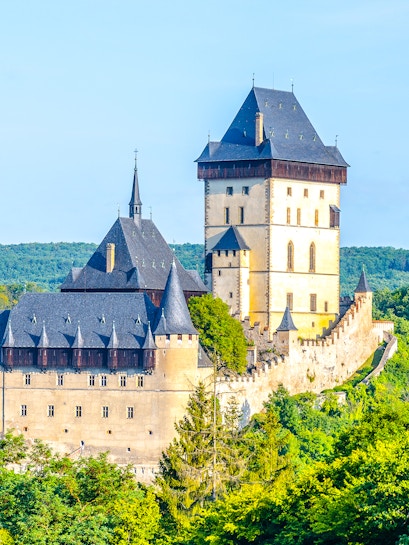 Karlstejn Castle with Gothic architecture surrounded by lush greenery in the Czech Republic.