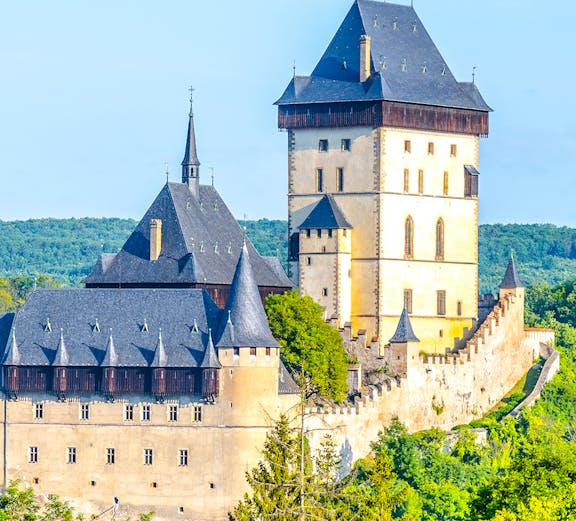 Karlstejn Castle with Gothic architecture surrounded by lush greenery in the Czech Republic.