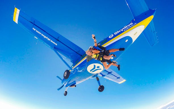 Tandem skydiving over Airlie Beach with instructor and skydiver exiting plane.
