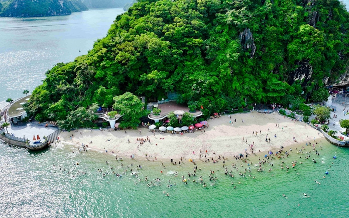Aerial view of Titop Island beach with tourists swimming and relaxing.