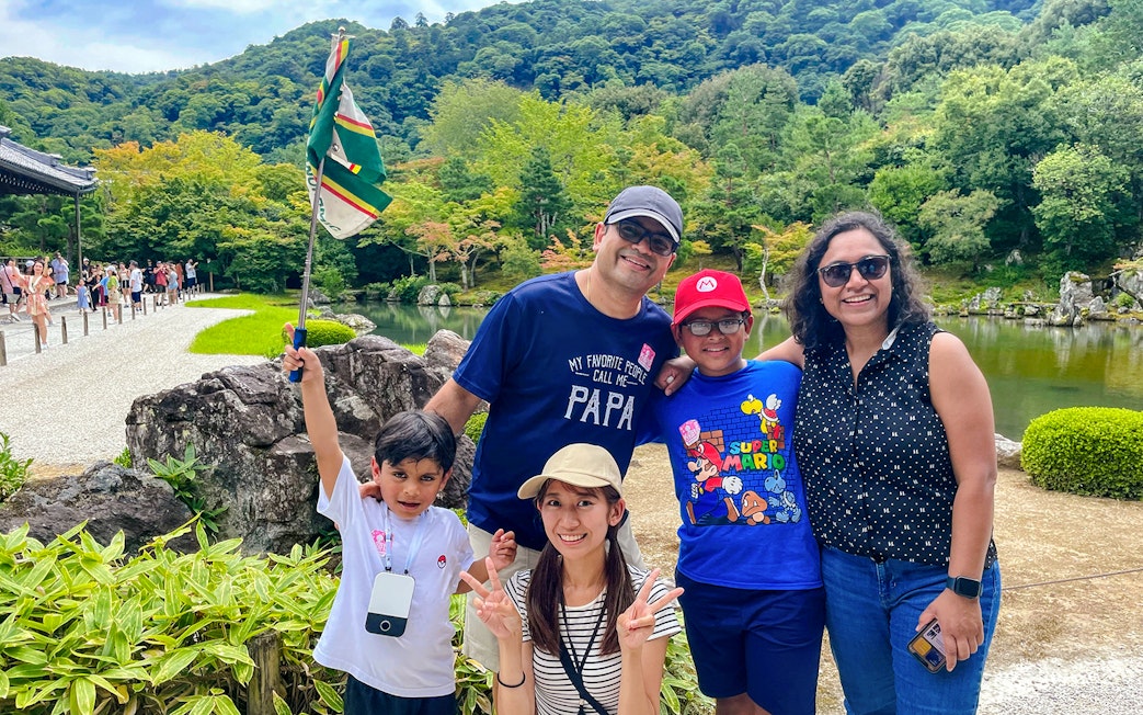Family enjoying a guided day trip in Kyoto with scenic garden and pond in the background.