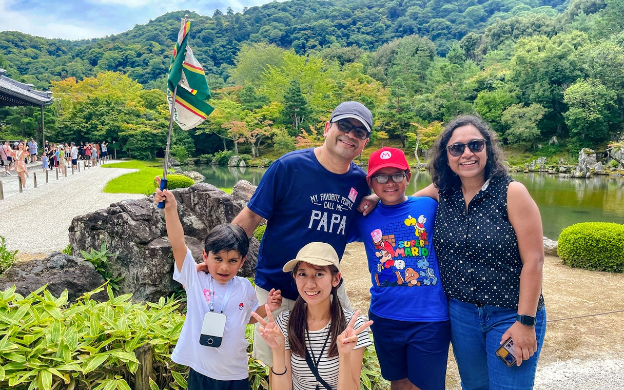 Family enjoying a guided day trip in Kyoto with scenic garden and pond in the background.