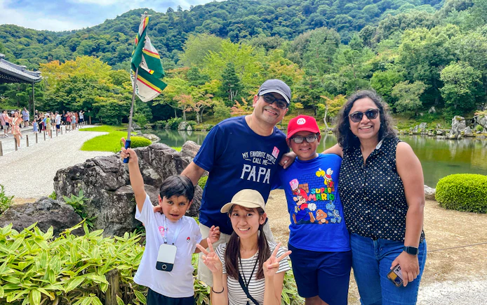 Family enjoying a guided day trip in Kyoto with scenic garden and pond in the background.