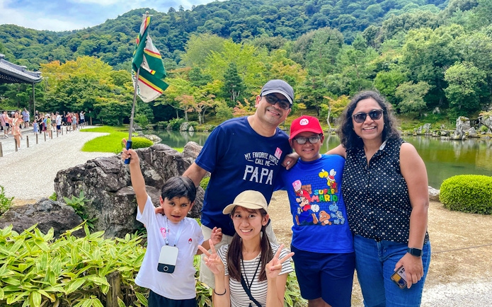 Family enjoying a guided day trip in Kyoto with scenic garden and pond in the background.