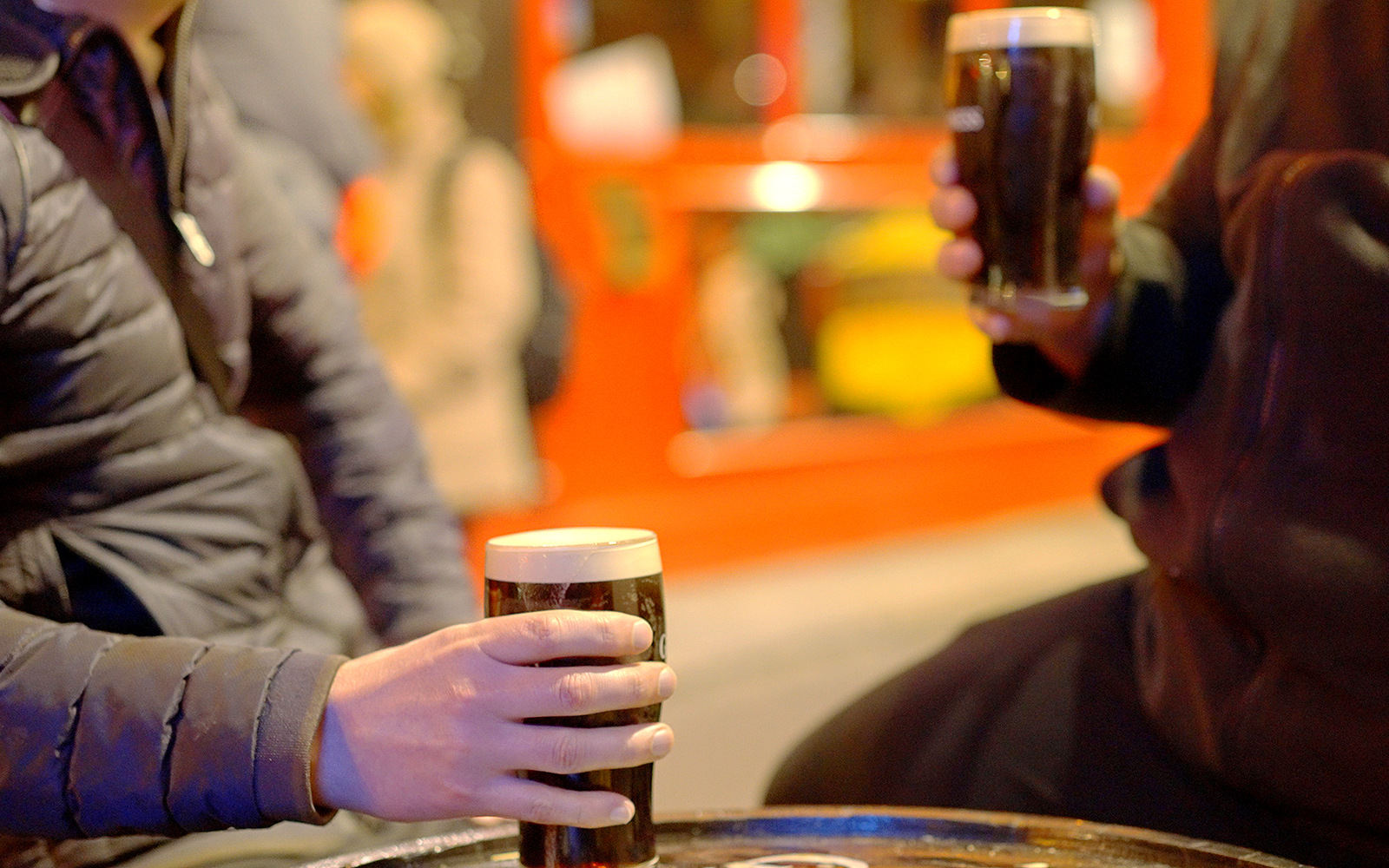 Two people holding pints of dark beer at an outdoor pub in Dublin.