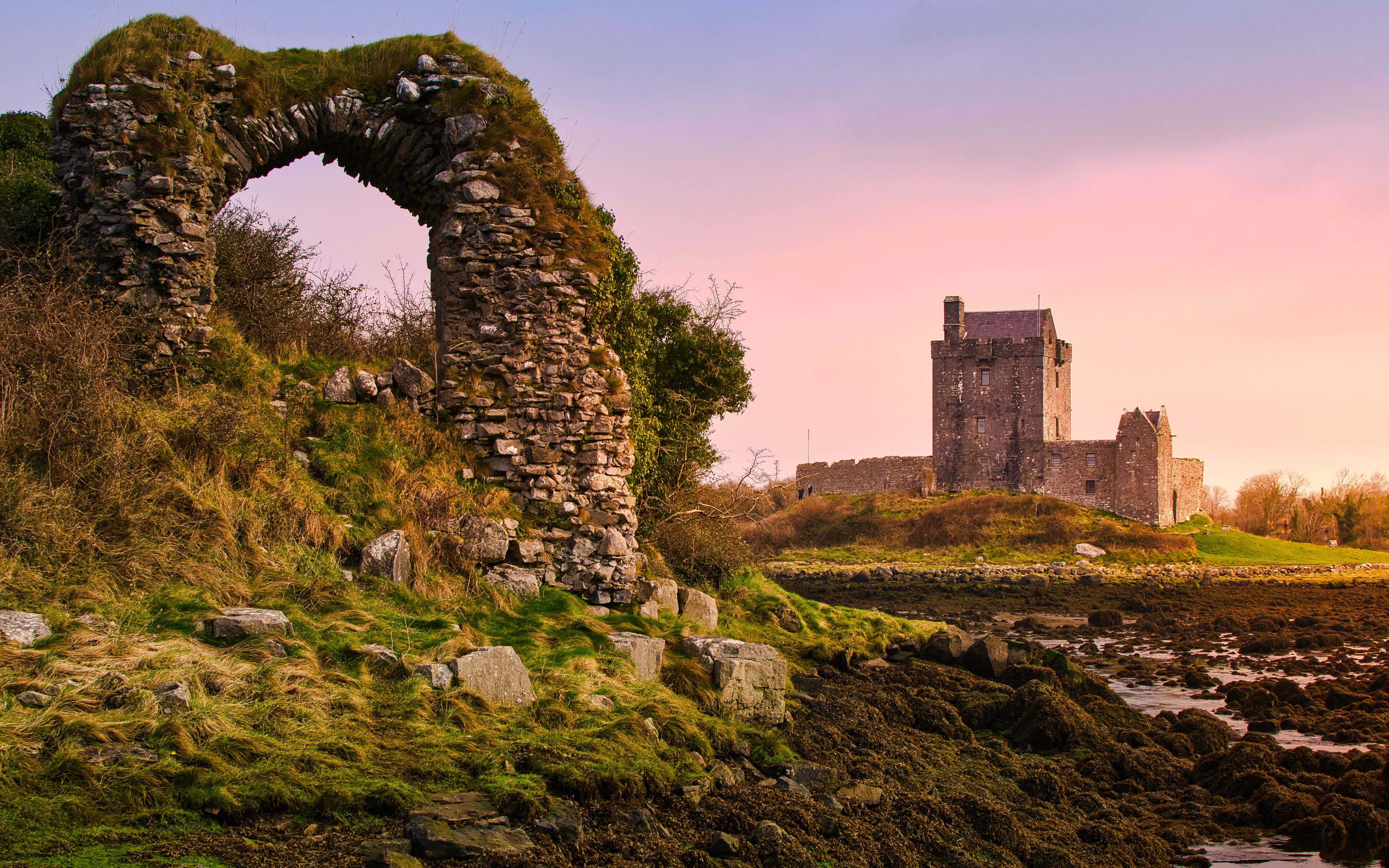 Sunset over Dunguaire Castle with stone archway in foreground, County Galway, Ireland.