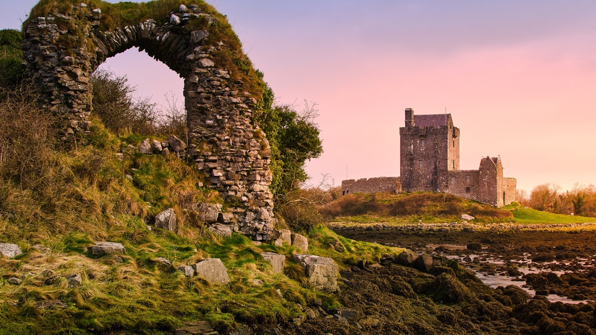 Sunset over Dunguaire Castle with stone archway in foreground, County Galway, Ireland.