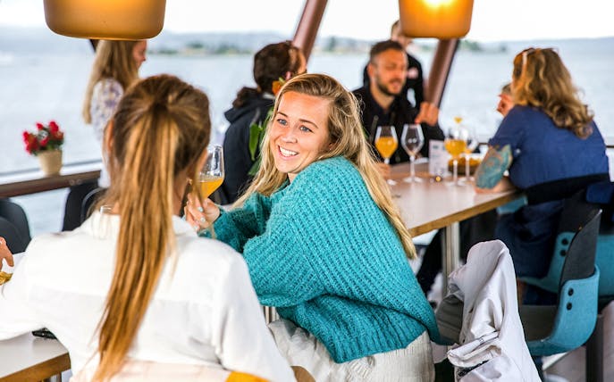 Brunch gathering on a boat in Oslo with people enjoying drinks and conversation.