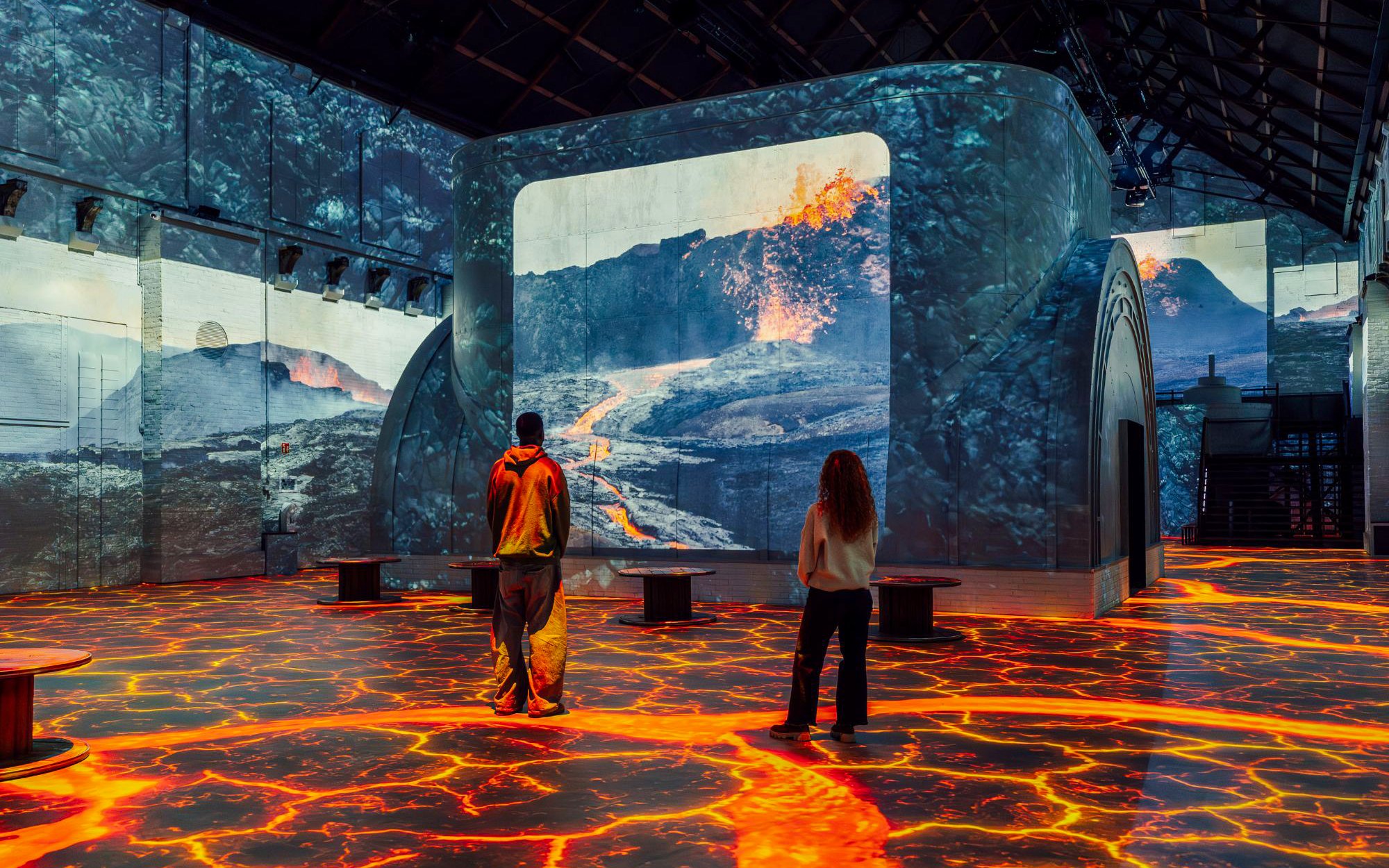 Visitors viewing volcanic eruption projections at Dino Exhibition, Fabrique des Lumières.