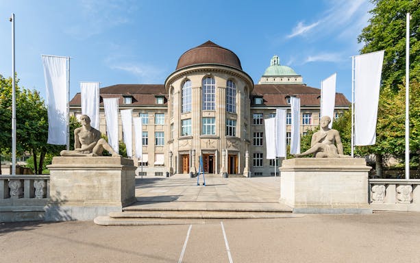 Zürich University main building with statues and flags on the Best of Zürich City Tour.