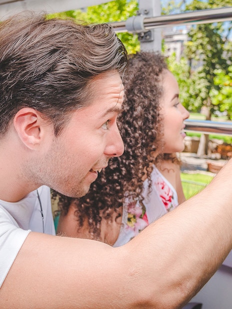 Tourists enjoying Santiago Hop-on Hop-off bus tour, pointing at city sights.