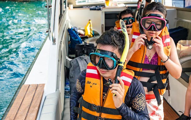 Tourists preparing for snorkeling at Nusa Penida, Bali, wearing life jackets and snorkel gear on a boat.