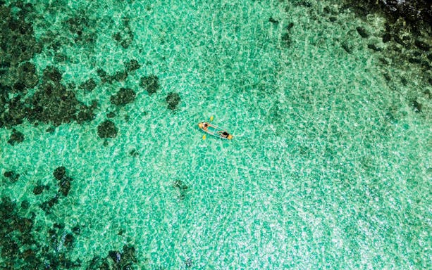 Canoeing on clear turquoise waters at Banana Beach, Koh Hey.