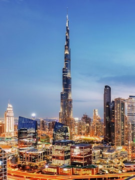 Dubai downtown skyline with Burj Khalifa illuminated at dusk.