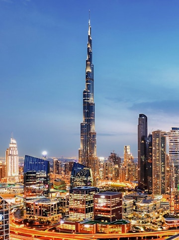 Dubai downtown skyline with Burj Khalifa illuminated at dusk.