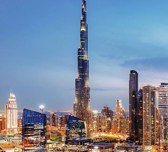 Dubai downtown skyline with Burj Khalifa illuminated at dusk.