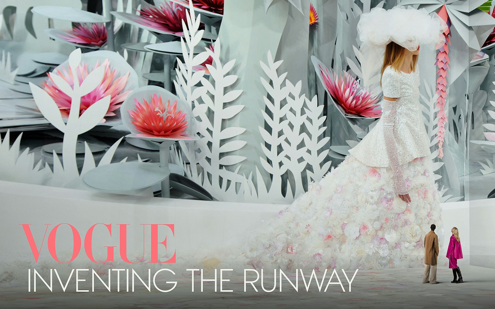 Vogue: Inventing the Runway exhibit with floral backdrop and fashion model.
