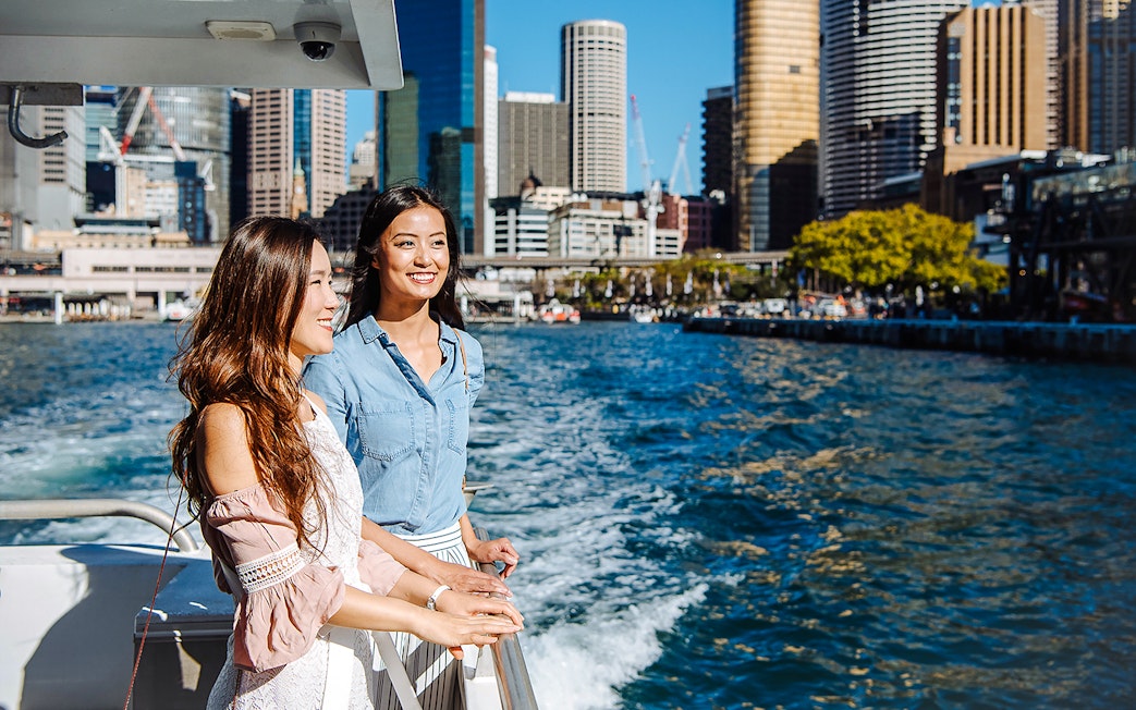 Women enjoying a cruise on Sydney Harbour with city skyline in the background.