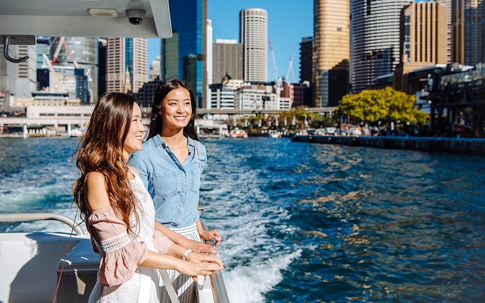 Women enjoying a cruise on Sydney Harbour with city skyline in the background.