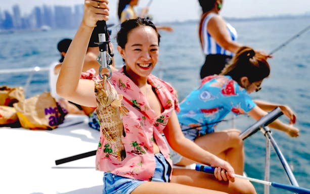 Woman holding a fish on a yacht during a fishing trip.