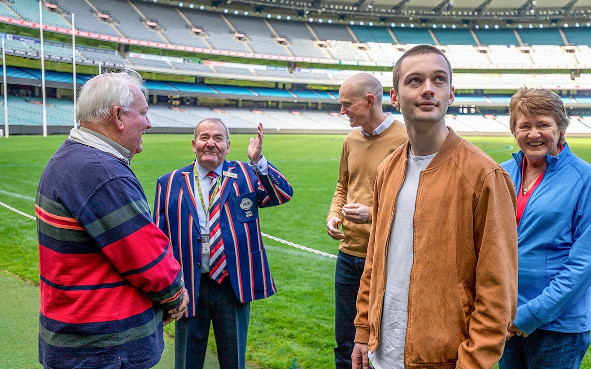 Tour group with guide at Melbourne Cricket Ground field.