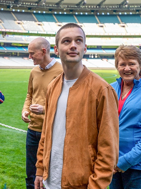 Tour group with guide at Melbourne Cricket Ground field.