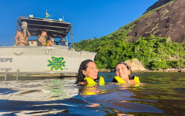 Tourists swimming near a boat in Guanabara Bay, Rio de Janeiro.