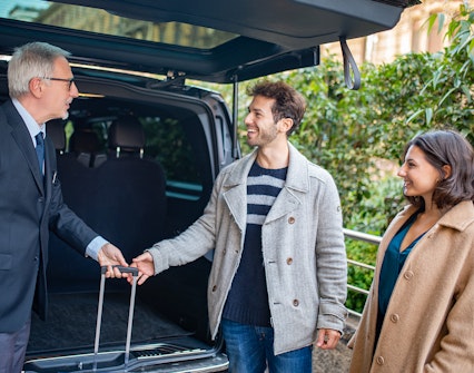 Shuttle driver assisting passengers with luggage.
