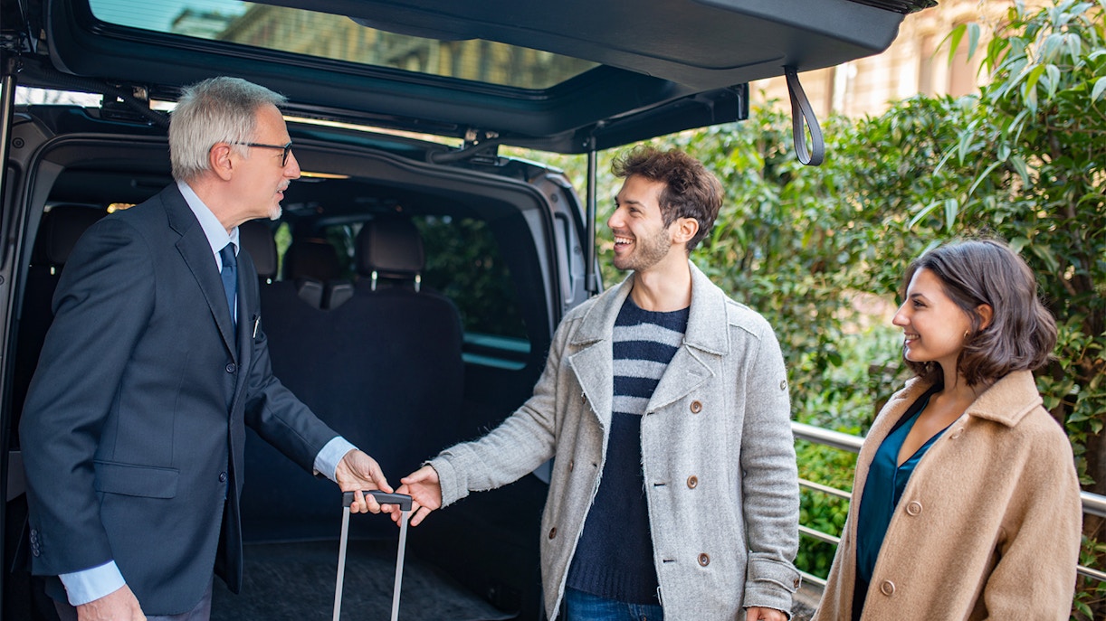 Shuttle driver assisting passengers with luggage.