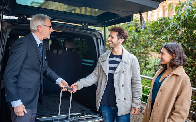Shuttle driver assisting passengers with luggage.