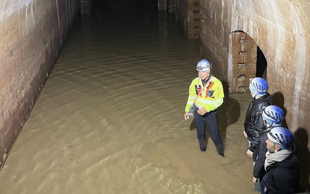 Guide leading a group through an underground waterway in Ancona.