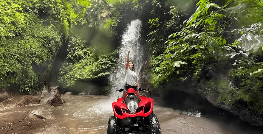 Person on ATV in front of waterfall during Ubud Kuber Trek in Bali.