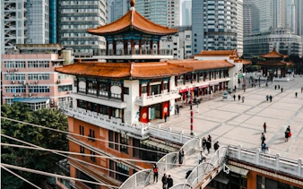 Traditional Chinese architecture in Chongqing cityscape with people walking on a bridge.