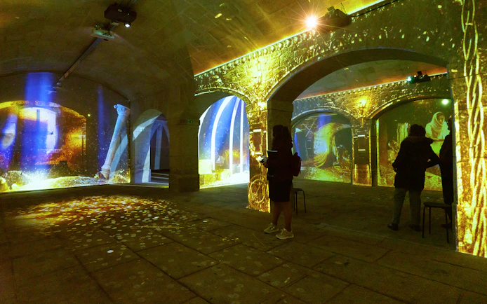 Porto Legends immersive experience with projections and audioguide in a historic stone hall.