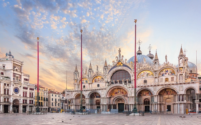 St. Mark's Basilica exterior in Venice with ornate facade and domes at sunset.